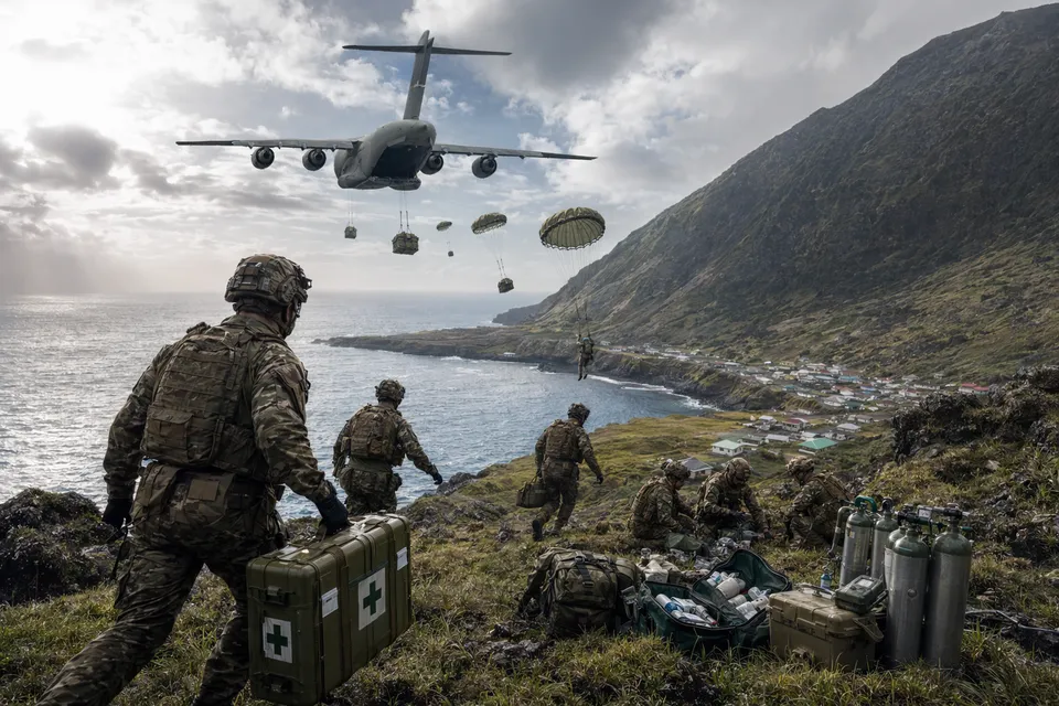 Illustration of an RAF transport aircraft dropping parachutists and medical supplies over a remote volcanic island